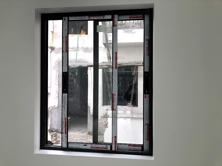 Cửa sổ nhôm kính đang lắp đặt nhìn ra công trình xây dựng bên ngoài